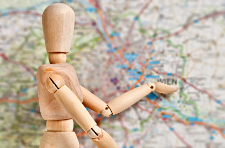 A wooden mannequin standing on a road map, pointing